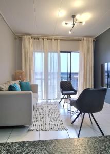a living room with a couch and chairs and windows at The Convenient Corner in Nelspruit