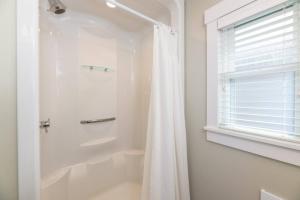a white bathroom with a shower curtain and a window at Sunny Shores - Lake days, Pool dips & Concerts in Dockham Shore +31 photos