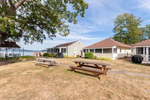 two picnic tables in the grass in front of houses at Sunny Shores - Lake days, Pool dips & Concerts in Dockham Shore