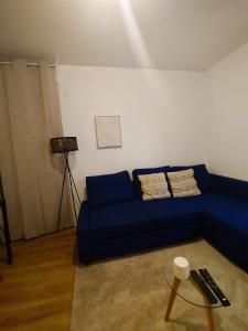 a living room with a blue couch and a table at Superbe appartement proche la Défense et Paris in Bezons +9 photos