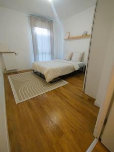 a bedroom with a bed and a wooden floor at Superbe appartement proche la Défense et Paris in Bezons
