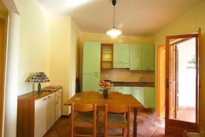 una cucina con tavolo in legno e armadi verdi di Residence Villaggio Smedile a Capo Vaticano