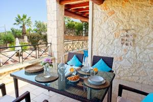 a patio with a table and chairs on a balcony at Villa Petalouda in Tragaki
