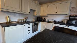 a kitchen with white cabinets and a black counter top at Sensinhome in Dover