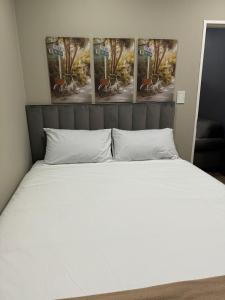 a bed in a room with four paintings on the wall at Closer to CBD by UrbanCove in Nelspruit