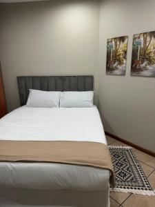 a bed in a bedroom with two pictures on the wall at Closer to CBD by UrbanCove in Nelspruit