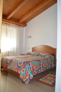 a bed with a colorful comforter in a bedroom at La Laguna in Hinojosa de la Sierra