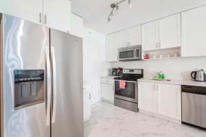 a kitchen with white cabinets and a stainless steel refrigerator at Ocean Breeze Retreat in Miami Beach in Miami Beach