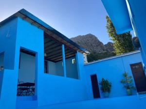 a view of a blue house with mountains in the background at Dar Lala Zhour in Aïn Bouchrik