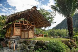 a small hut with a palm tree in a field at Finca Aveterra, Luxurious Riverside Retreat in Mindo