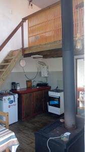 a kitchen with a stove and a staircase in a room at La casita in Barra de Valizas