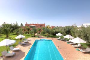 a swimming pool with chairs and umbrellas at Villa Dar Mya Palmiers in Marrakesh