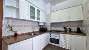 een witte keuken met witte kasten en een spoelbak bij Dragoeiro Duplex by Sam Houses in Ribeira Brava