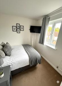 a bedroom with a bed and a television and a window at Colchester Retreat 4br 2bath Ample Street Parking in Colchester +17 photos