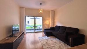 een woonkamer met een zwarte bank en een televisie bij Dragoeiro Duplex by Sam Houses in Ribeira Brava