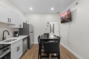 a kitchen with white cabinets and a table with chairs at Modern 2 bedroom 1 bath unit 2 Near Airport, Xfinity Arena and Eagles Stadium in Philadelphia