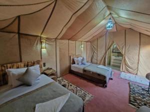 a bedroom with two beds in a tent at Merzouga Desert Tents in Merzouga