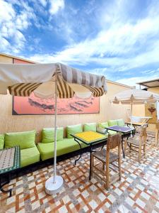 a patio with a couch and tables and umbrellas at Sun Hostel in Marrakech