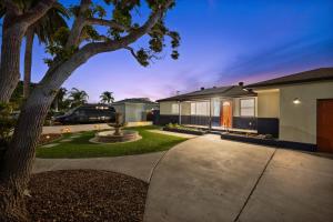 a house with a tree in front of a driveway at Cozy Room with Hot Tub, Pool, Sauna & Gym Near Beach in Oceanside