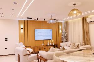 ein Wohnzimmer mit weißen Möbeln und einem Bildschirm in der Unterkunft شقة فندقية فاخرة شارع جيهان الرئيسي بجوار النيل و جامعه المنصوره in Mansoura