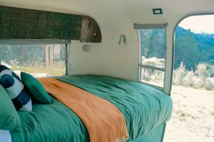 a bed in the middle of a rv with a window at Airstream Caravan at Matakana Retreat in Matakana