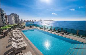 a swimming pool with lounge chairs and the ocean at Barceló Colon Miramar Salinas suite in Salinas