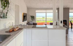 a kitchen with white cabinets and a view of the ocean at 3 Bedroom Amazing Home In Sjølund in Binderup Strand