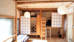 ein Zimmer mit Etagenbetten, auf denen Menschen sitzen in der Unterkunft konatoko in Wakayama