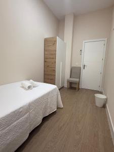 een witte slaapkamer met een bed en een stoel bij Apartamento Orilla de Triana Luxury in Sevilla +33 foto's