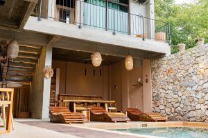 a patio with wooden tables and chairs next to a pool at Casa Ampa Zikatela- Brisas de Zicatela- Puerto Escondido in Brisas de Zicatela