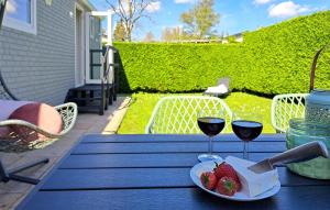 a table with two glasses of wine and a plate of strawberries at Beautiful Home In Heinkenszand With Wifi in Graszode +23 photos