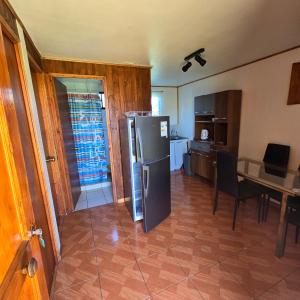 una cucina con frigorifero e tavolo con sedie di Cabañas Manuara a Hanga Roa