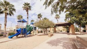 ein Spielplatz mit Rutsche in einem Park mit Palmen in der Unterkunft Casa Sofia de una planta in Hermosillo