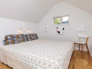 a white bedroom with a bed and a chair at 6 person holiday home in Stege in Tyrholm