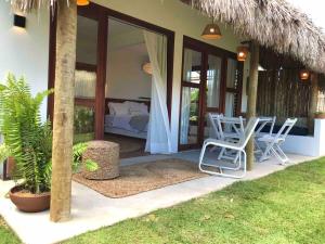 a patio with two chairs and a bed in a house at Chalé Koa Flora - PRAIA DE MOITAS in Praia de Moitas