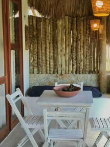 a table with two chairs and a bowl on top of it at Chalé Koa Flora - PRAIA DE MOITAS in Amontada
