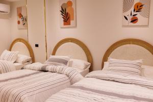 3 Betten in einem Zimmer mit weißer Bettwäsche in der Unterkunft شقة فندقية فاخرة شارع جيهان الرئيسي بجوار النيل و جامعه المنصوره in Mansoura