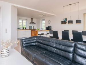 a living room with a leather couch and a kitchen at 5 star holiday home in Rømø in Sønderby