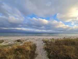 a sandy beach with the ocean on a cloudy day at 6 person holiday home in Væggerløse in Marielyst +24 photos