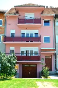 um edifício cor-de-rosa com duas varandas em Guest House Trajkovic em Jagodina