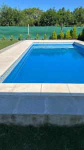 a swimming pool with blue water in a yard at Quinta el roquedal in Baradero