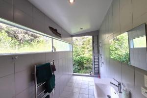 a bathroom with a sink and a window at beach bush retreat at Leigh in Leigh +5 photos