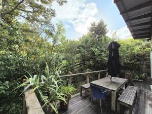 a wooden deck with a wooden table and a bench at beach bush retreat at Leigh in Leigh