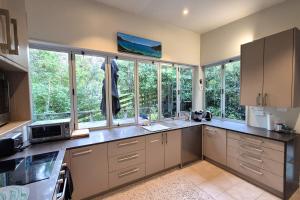 a kitchen with large windows and a large counter top at beach bush retreat at Leigh in Leigh