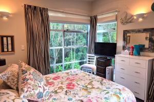 a bedroom with a bed and a large window at beach bush retreat at Leigh in Leigh