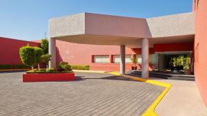 a large red building with a sidewalk in front of it at Fiesta Inn Aguascalientes in Aguascalientes