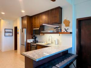 a kitchen with wooden cabinets and a granite counter top at Hibisco Belize in San Pedro