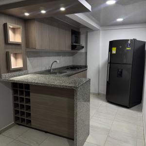a kitchen with a black refrigerator and a counter top at Bulevar Santa Rosa, apartamento nuevo y acogedor in Santa Rosa de Cabal +5 photos