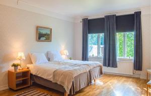 a bedroom with a large bed and two windows at Cozy Apartment In Storfors With Wifi in Storfors
