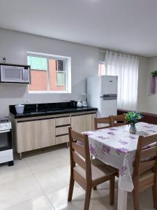 eine Küche mit einem Tisch und einigen Stühlen und einem Tisch und einer Küche mit in der Unterkunft Residencial Spader - Bombinhas in Bombinhas